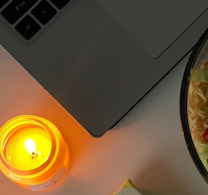 a small painting a candle a dish and a laptop on the desk